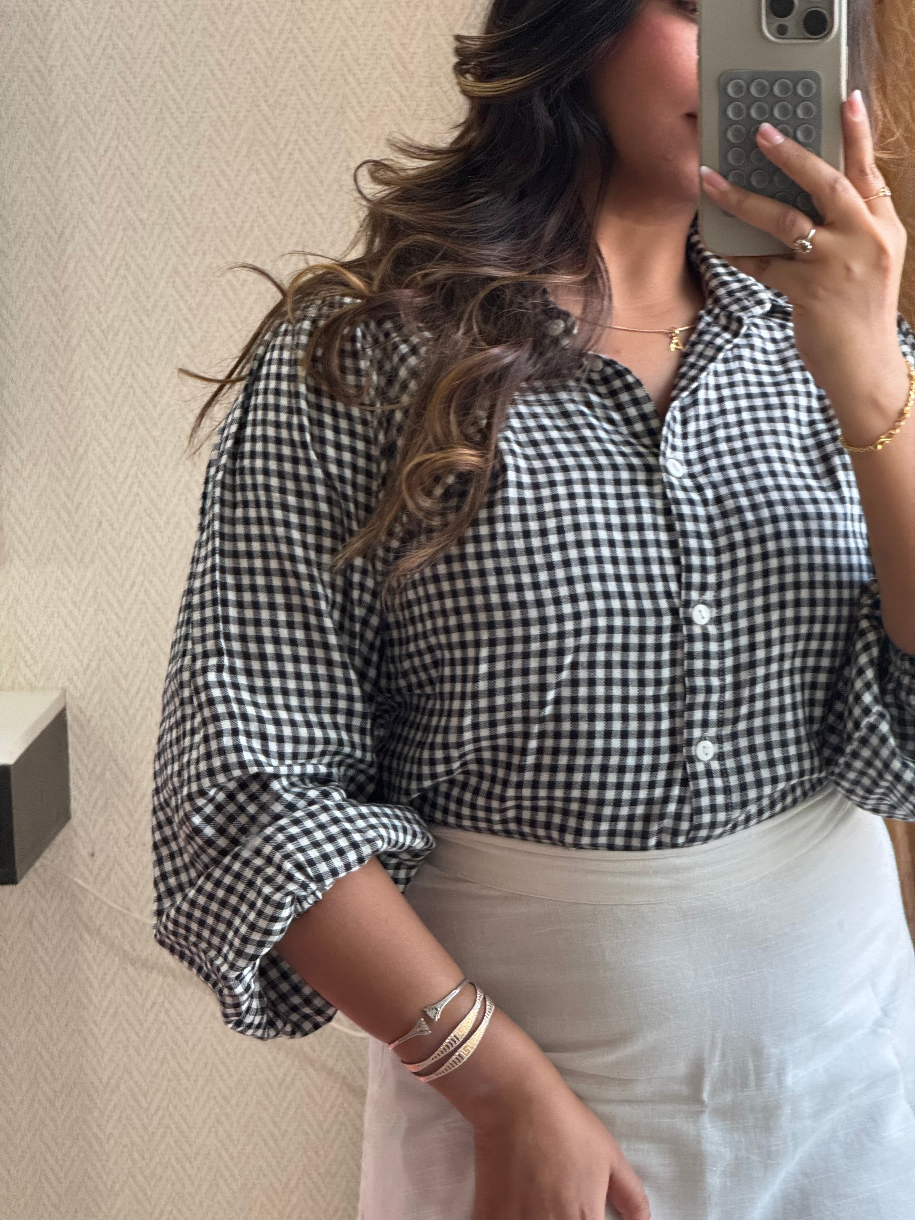 Person wearing a black and white checkered shirt on a beige couch